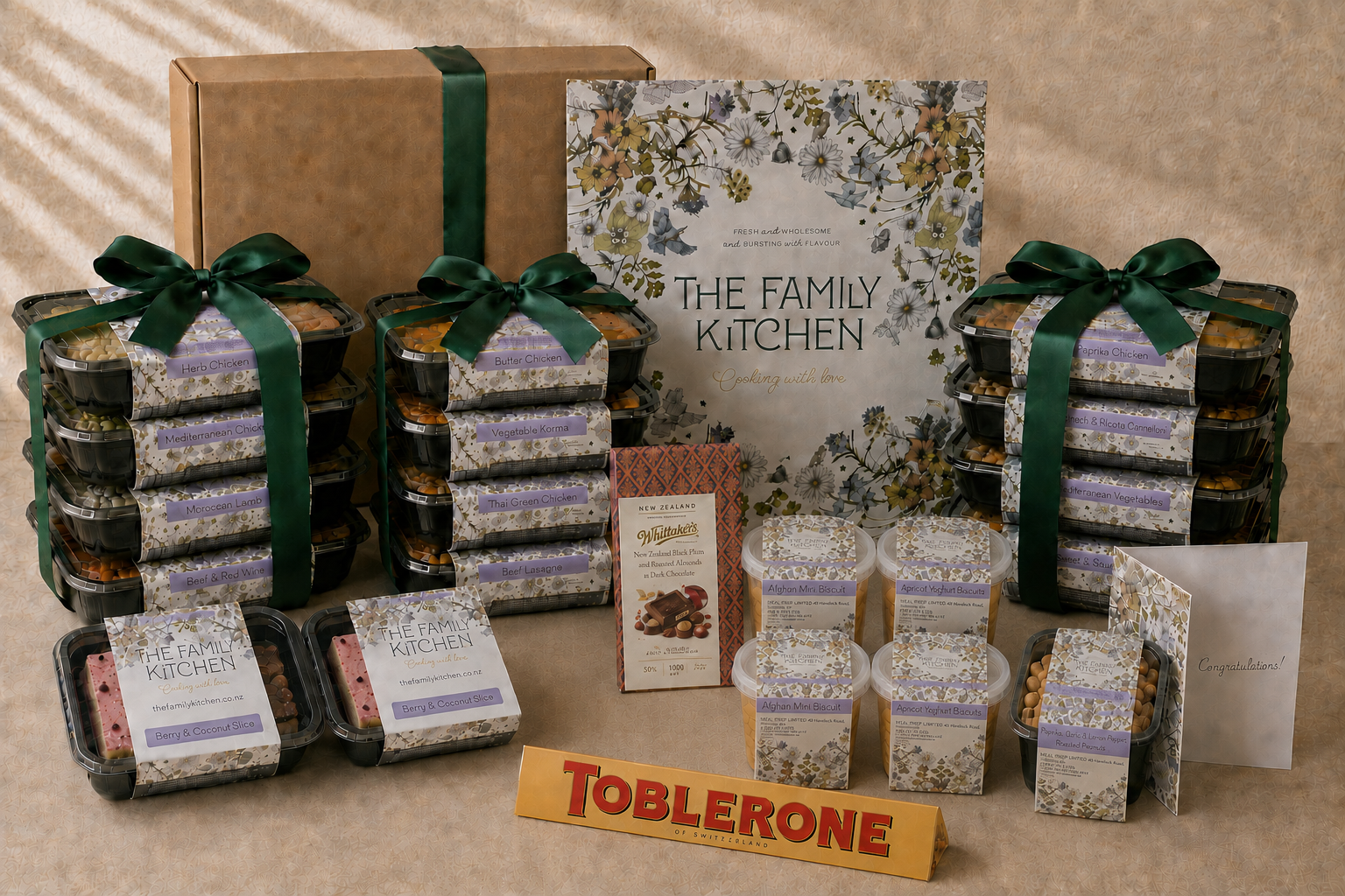 The Family Kitchen Grand Celebration gift with twelve chef-made meals, six desserts, Whittaker's chocolate, Toblerone, roasted peanuts and a premium card.