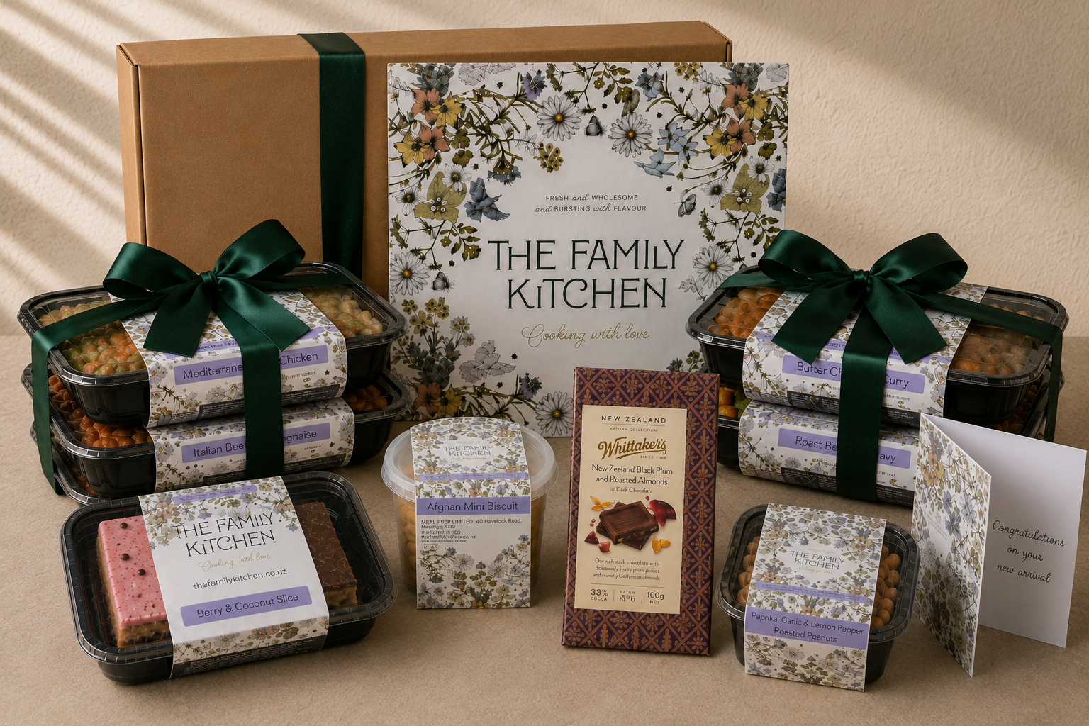 The Family Kitchen New Parent Essentials gift with four chef-made meals, two desserts, Whittaker's chocolate, roasted peanuts and a handwritten congratulations card.